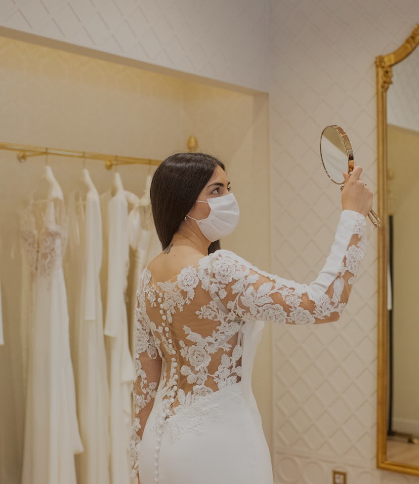 A bride is seen observing herself in a mirror at a David's Bridal store.