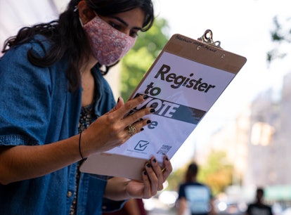 A woman holding a large election folder with the text 'Register to vote'