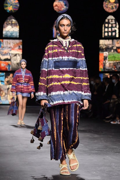  Model walking down the runway during dior's spring 2021 collection wearing a poncho and sandals