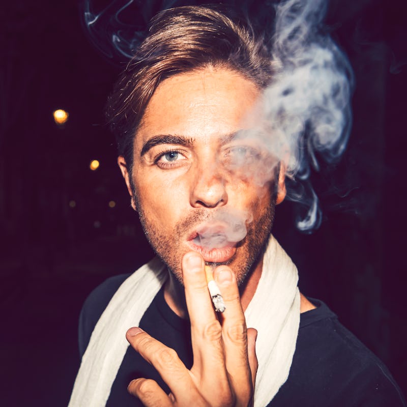 A close-up portrait of a man who has bad habits, smoking a cigarette