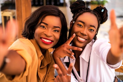 Two young Black women pose for a selfie after reuniting.