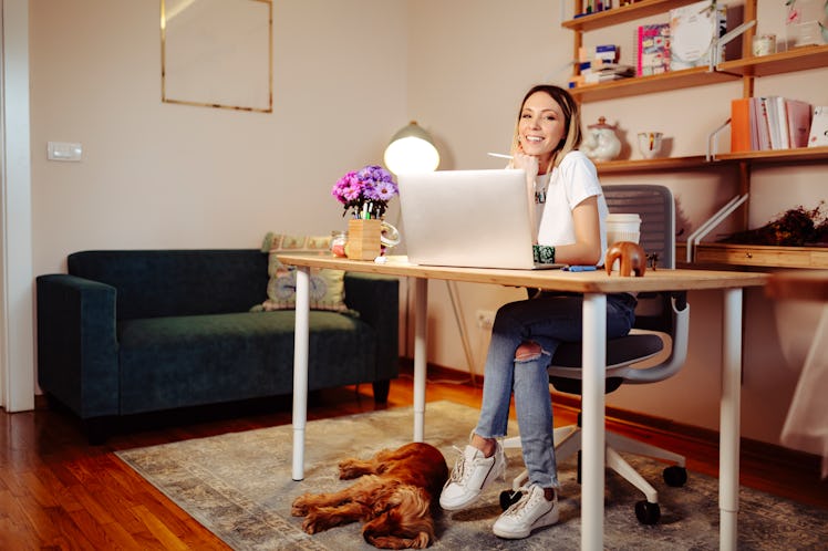 A young woman sits at a desk in her home office that she decorated all cozy for fall.