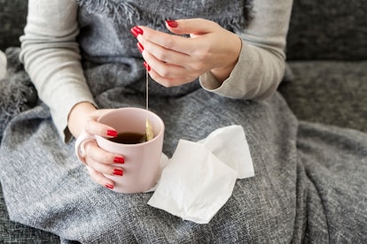 A woman makes tea to soothe her sore throat. Doctors explain what to know about how common sore thro...