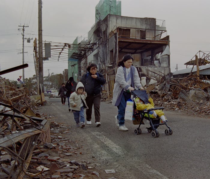 Aftermath of 1995 earthquake, family in street surrounded by rubble