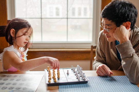 girl and dad playing chess
