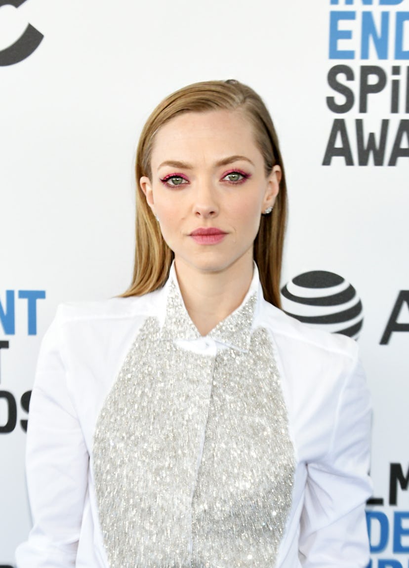 Amanda Seyfried with a deep side-part on her straight, slick blonde hairstyle. 