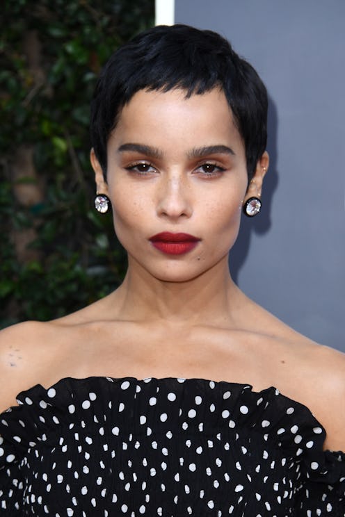 Zoë Kravitz posing on the red carpet with a pixie cut, cat eye, and a bold red lip.