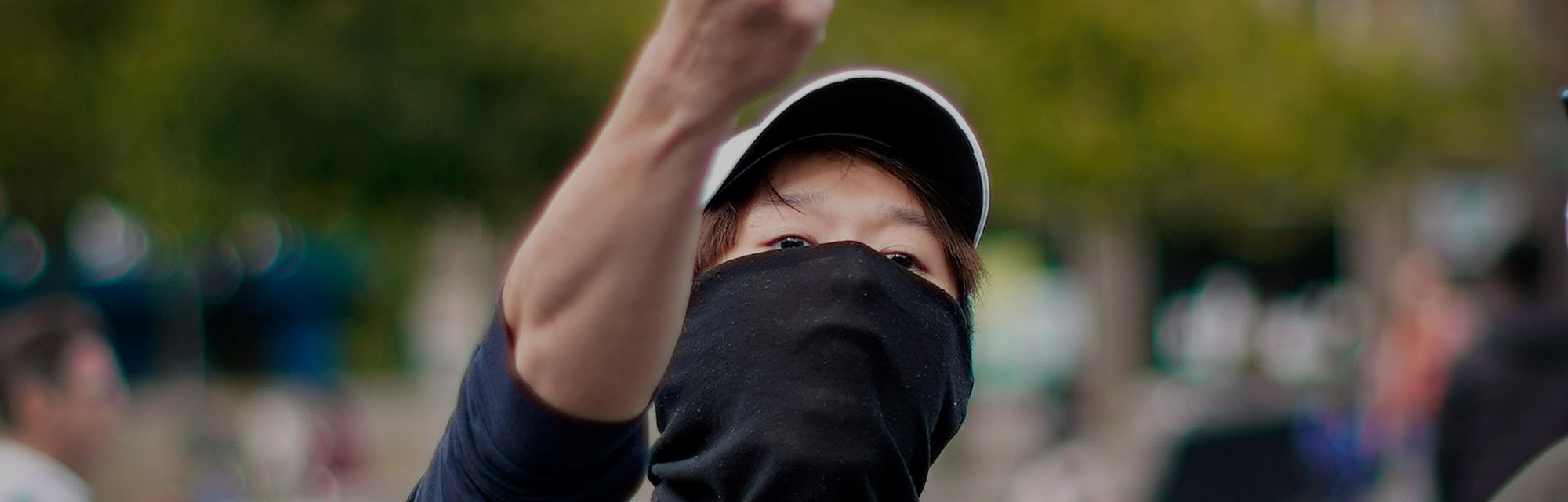 A protester in Hong Kong can be seen with a white hat and black face covering that hides the lower h...