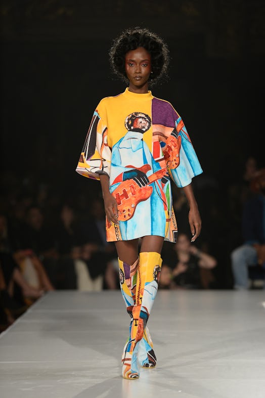 A model wearing a blue-orange shirt-dress and over-the-knee boots with the matching print