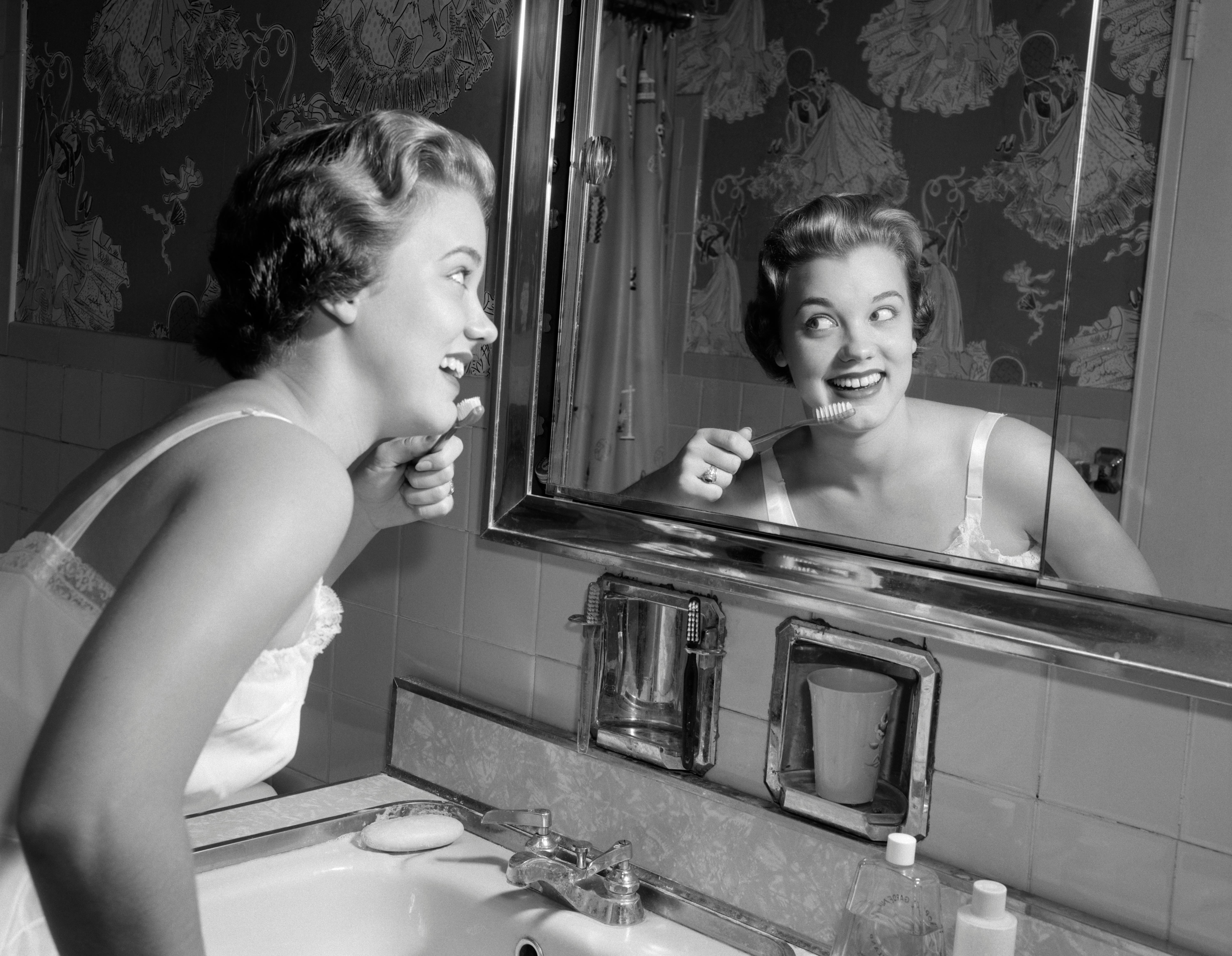 A woman brushes her teeth in the mirror. A dentist told the new york times how much pandemic stress ...
