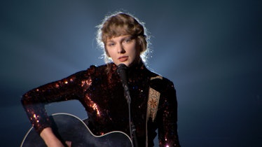 Taylor Swift wears a sequined dress and sings a song while playing guitar. 
