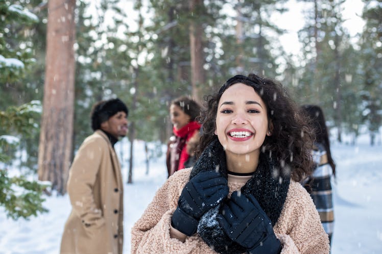 A happy girl stands on a snowy mountain with her friends behind her. 