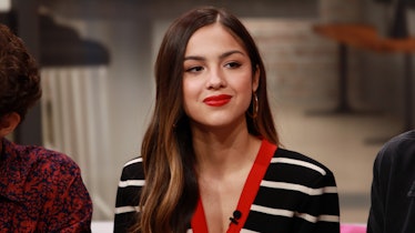 Olivia Rodrigo wears a white and black striped cardigan and red lipstick.
