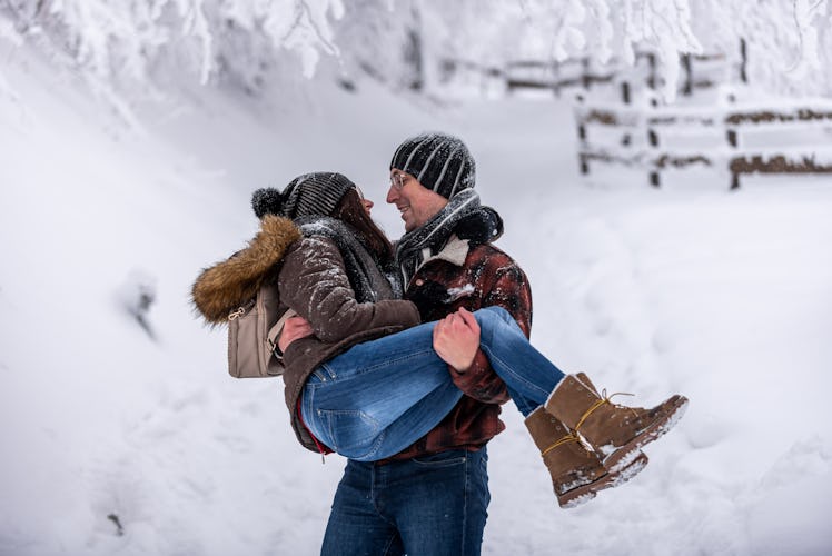 A happy couple plays in the snow in the mountains.