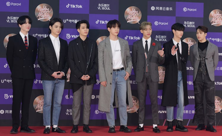 GOT7 stands on the red carpet in various suits. 