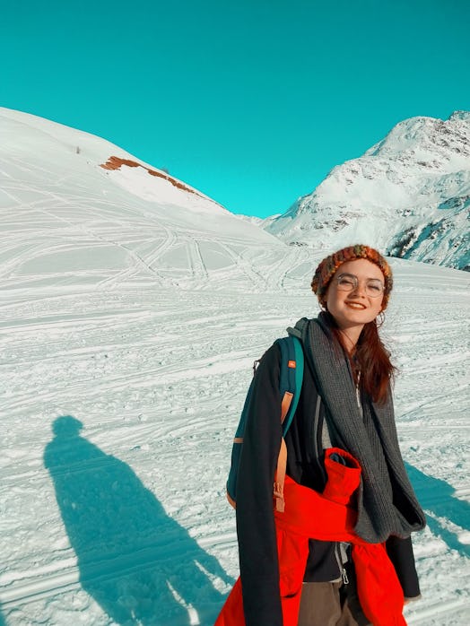 A young woman poses for a picture while on a winter hike in the mountains.