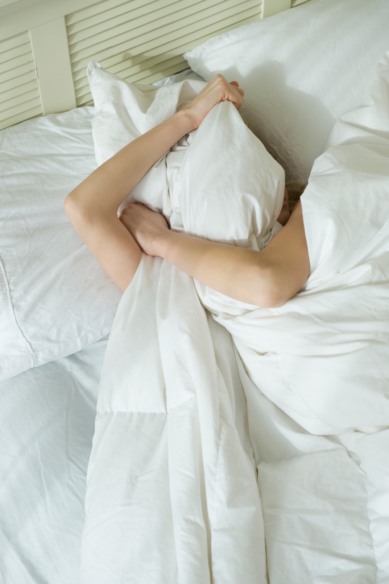 A woman in white sheets pulls the covers over her face after a night of drinking while she's dealing...