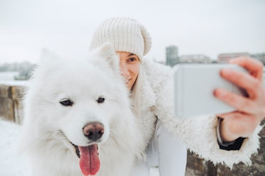 A young woman poses for a selfie with her dog in the middle of winter.