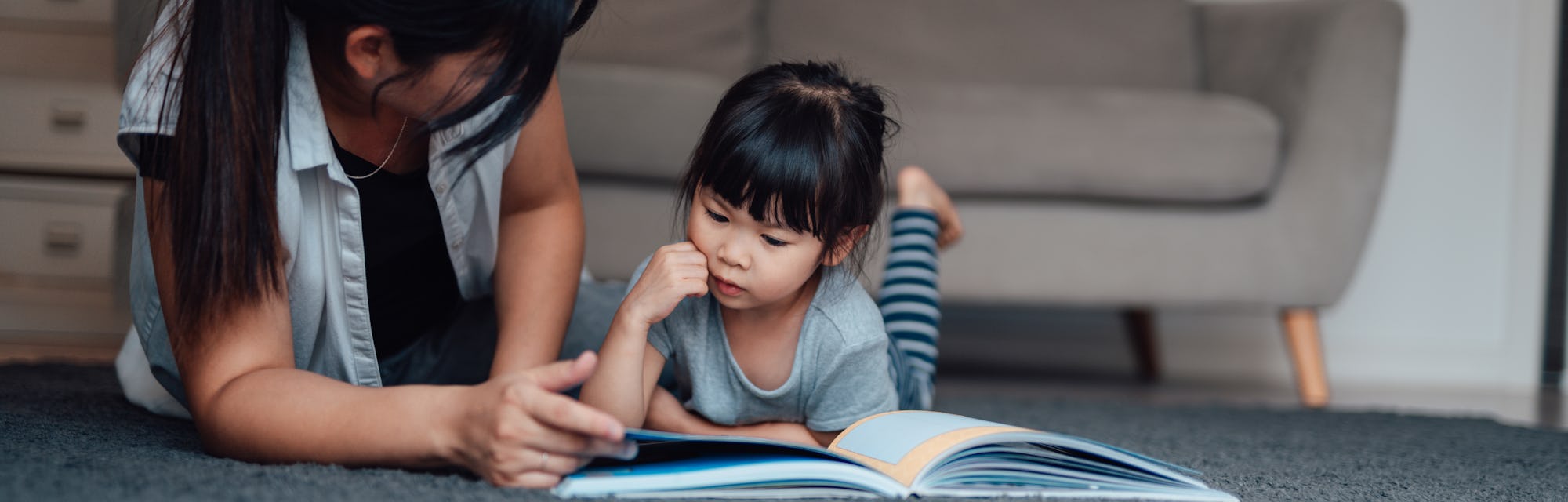 mom reading book to daughter