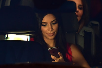 Kim Kardashian looks at her iPhone while sitting in the car. 