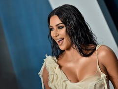 Kim Kardashian is happy while standing on the red carpet at an event. 