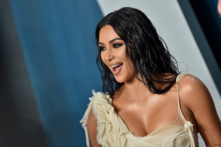 Kim Kardashian is happy while standing on the red carpet at an event. 