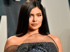 Kylie Jenner stands on the red carpet at an event with a sparkly gown. 