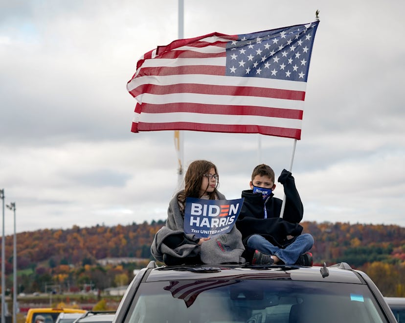 Two children wage an American flag and political signs supporting the Biden-Harris campaign.