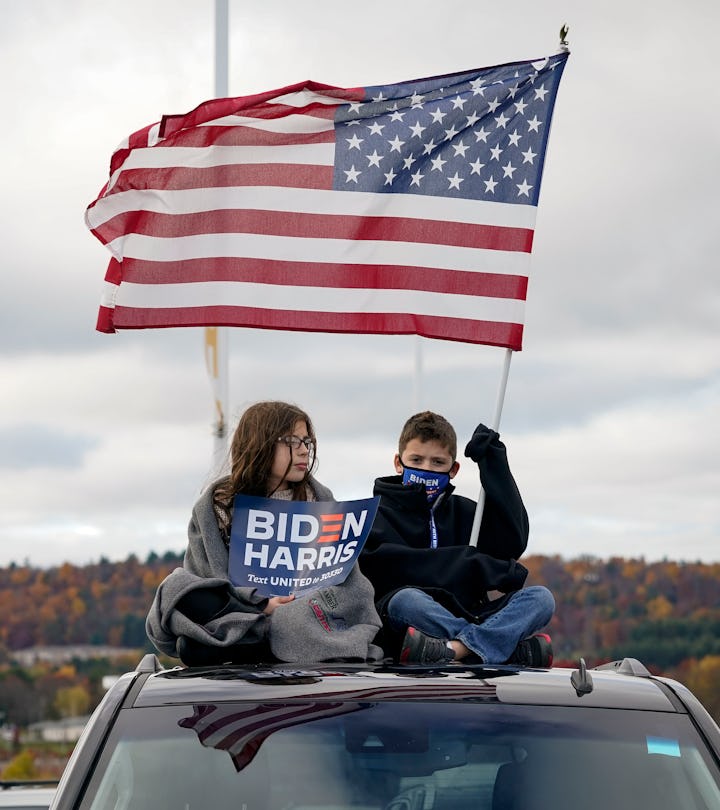 Two children wage an American flag and political signs supporting the Biden-Harris campaign.