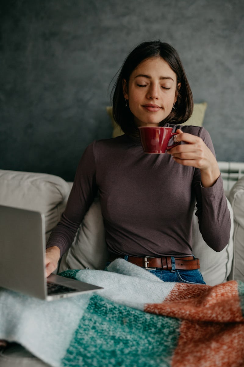 A woman wearing a blanket drinks a mug of tea. If you get cold easily it could be a sign of 9 health...