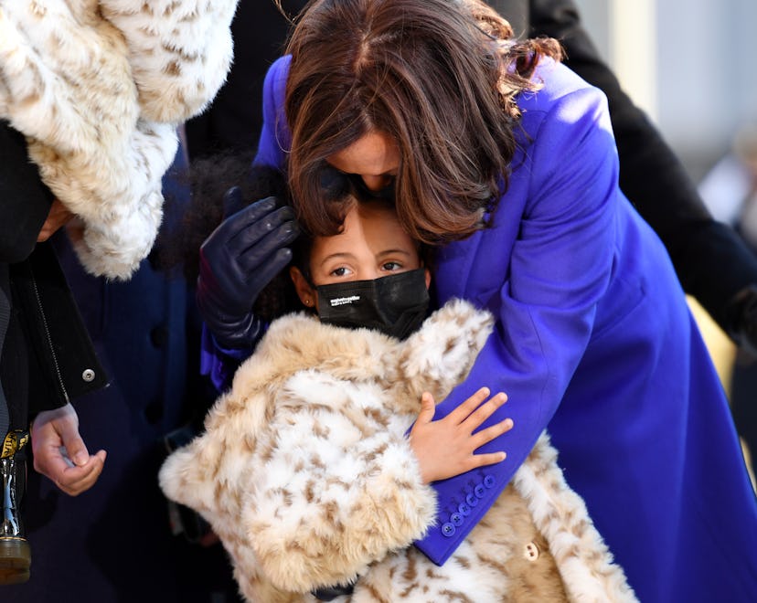 Kamala Harris hugging her great niece who is wearing a leopard coat and black face mask