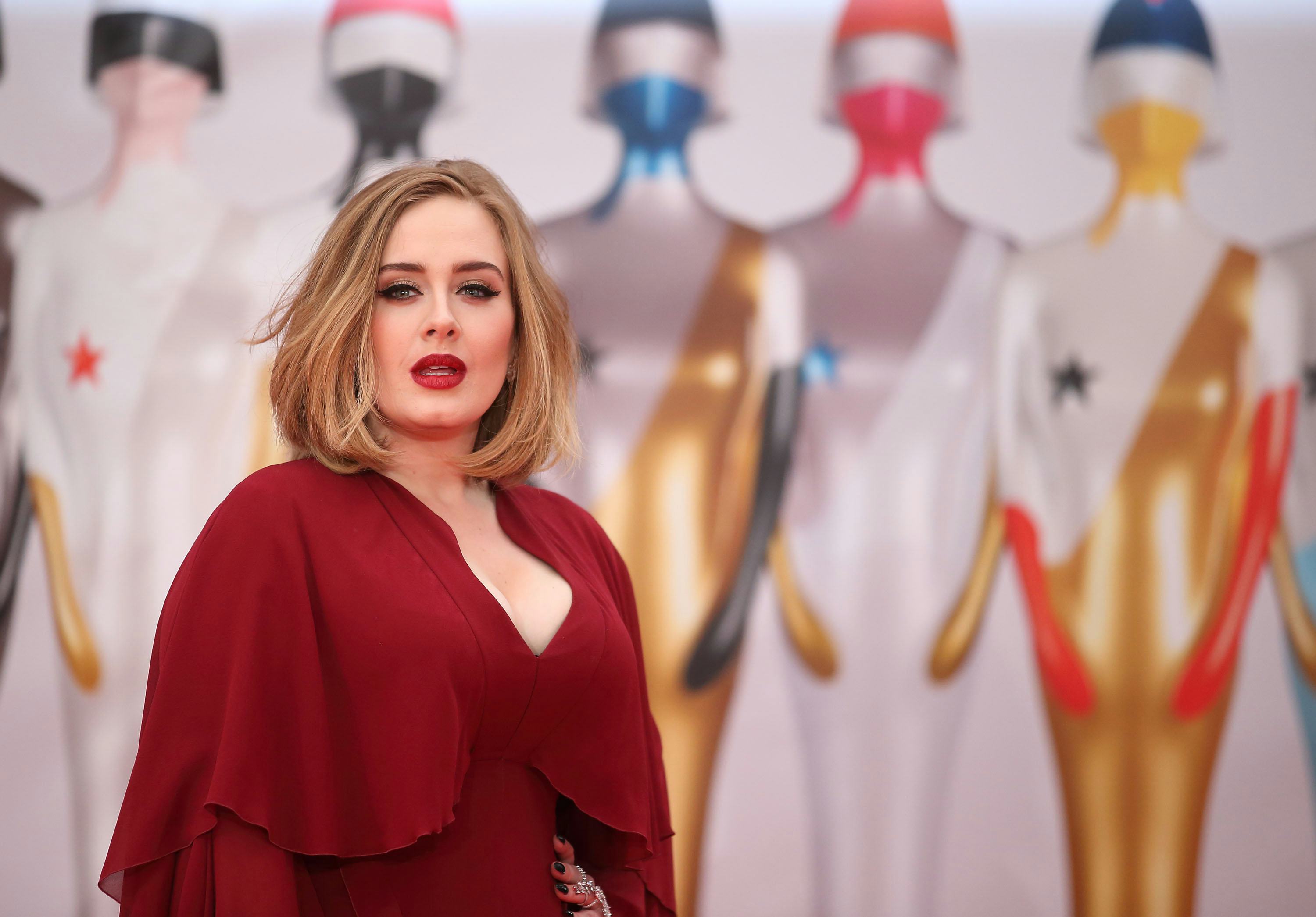 Adele posing in a layered red gown with deep cleavage