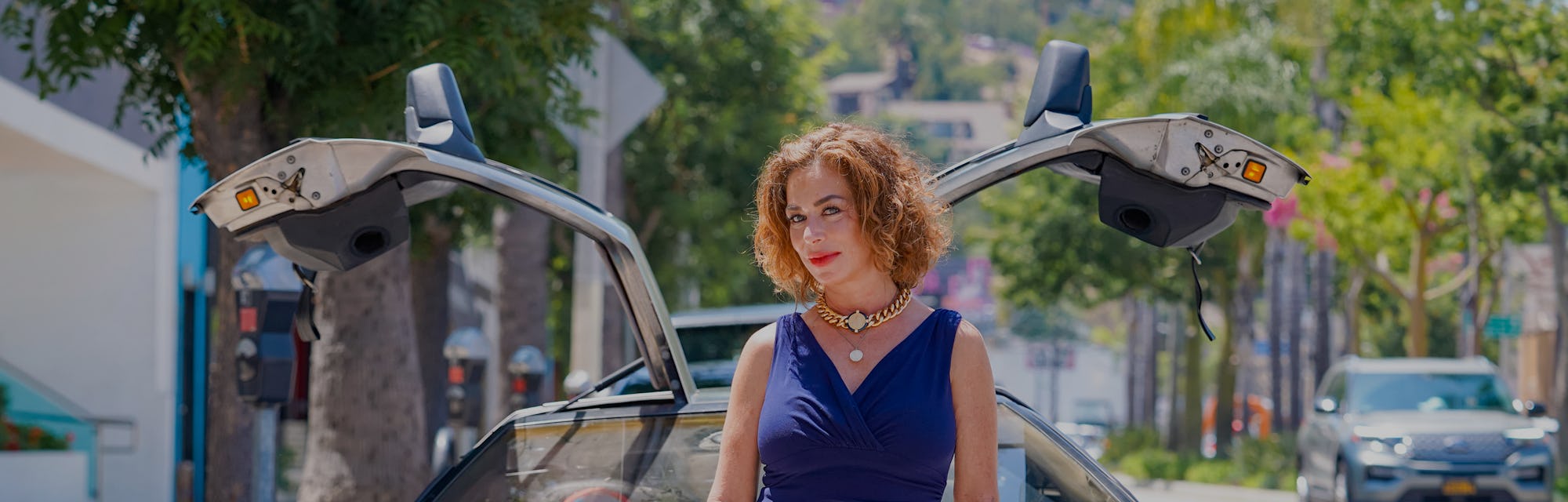 The DeLorean sports car pictured with a woman leaning on the hood.