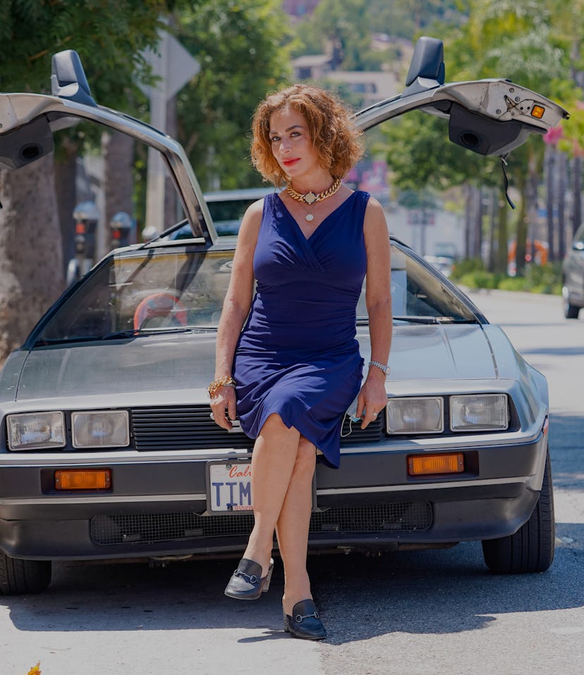 The DeLorean sports car pictured with a woman leaning on the hood.