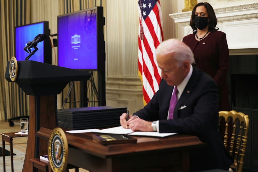 President Biden signs executive orders while Vice President Harris looks on. Former President Trump ...