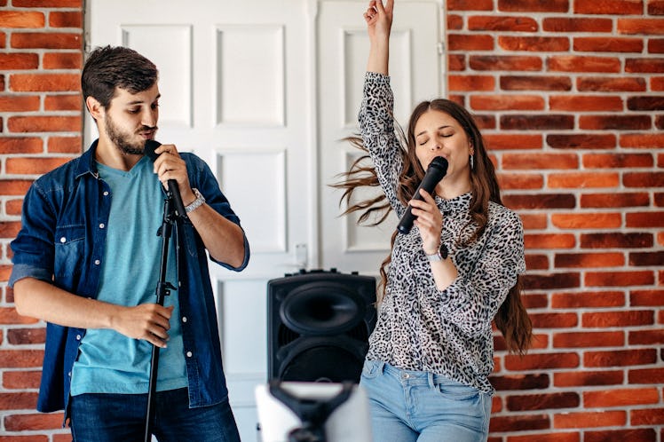 Two friends enjoy a round of karaoke for a super bowl zoom party.