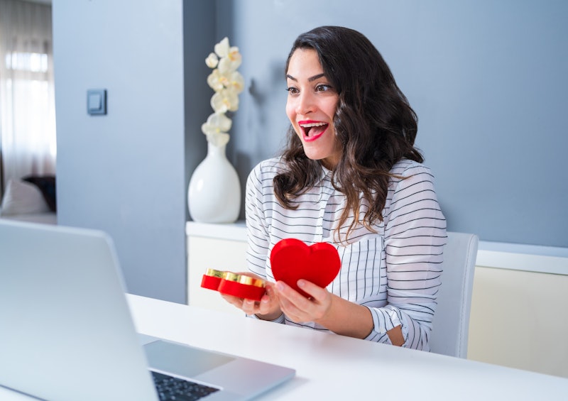 woman opening a heart-shaped box in front of her computer