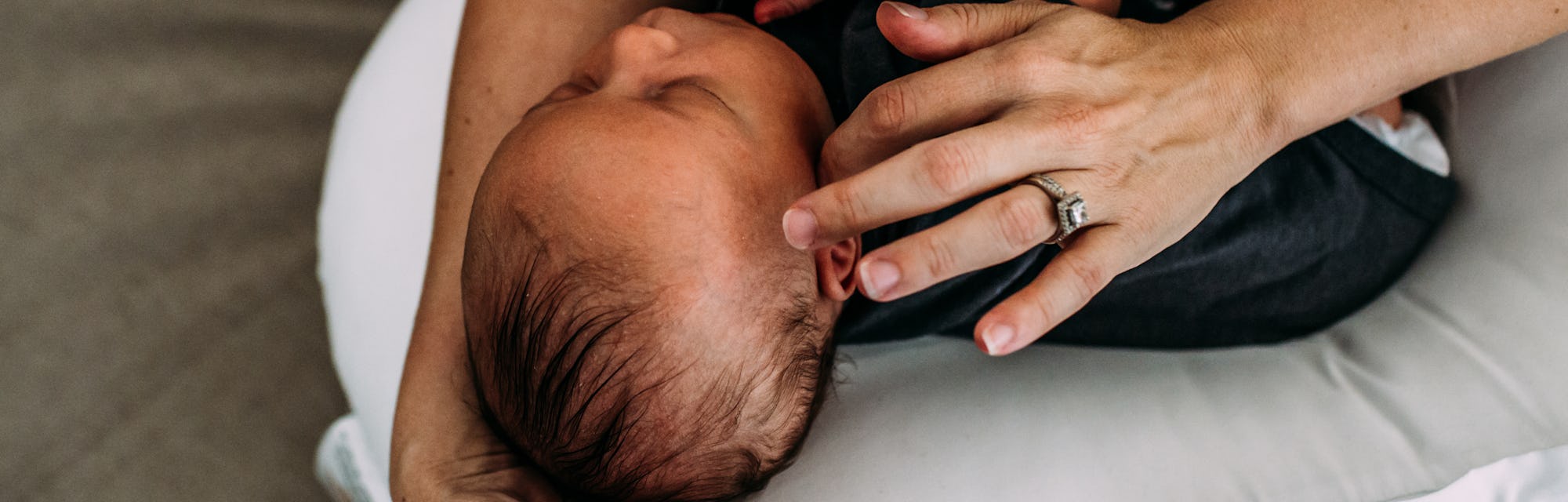 A mother holding her baby on her lap on a white nursing pillow