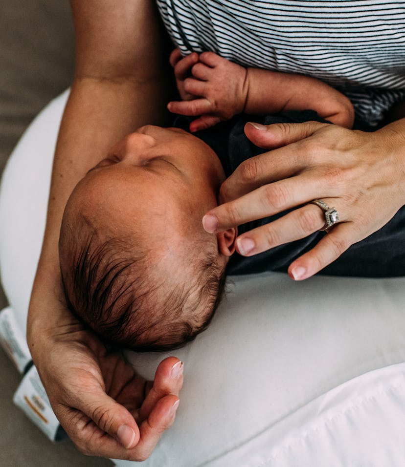 A mother holding her baby on her lap on a white nursing pillow