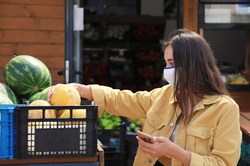 A person wearing a mask tries out melons at the grocery store. Experts explain how to protect yourse...