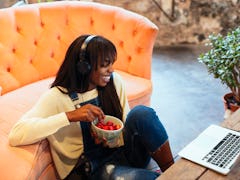 A young Black woman eats strawberries while video chatting and playing games with her friends on Gal...