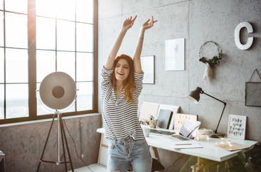 A woman dances in her living room at home while filming a TikTok video.