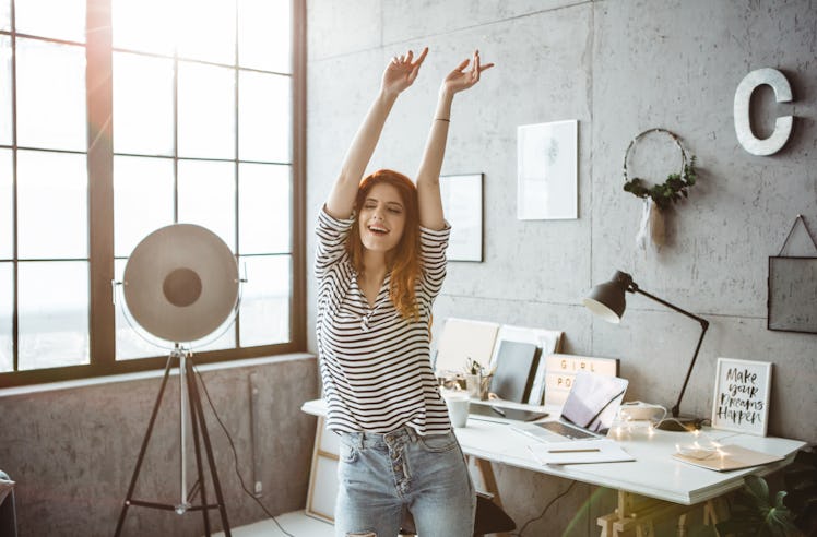 A woman dances in her living room at home while filming a TikTok video.