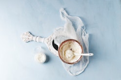 A bowl of shea butter used in skin care routine next to a white vintage mirror.