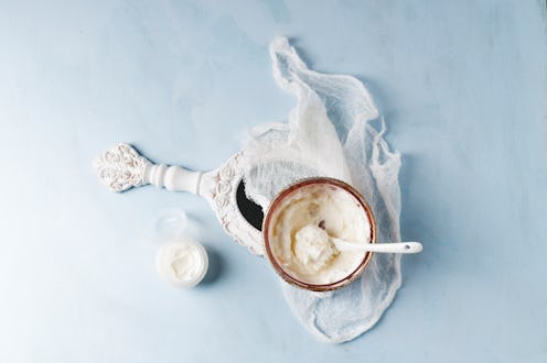 A bowl of shea butter used in skin care routine next to a white vintage mirror.