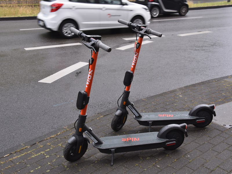 Two dockless electric scooters parked side by side on a sidewalk.