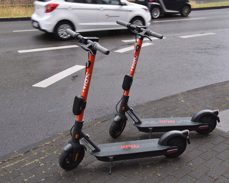 Two dockless electric scooters parked side by side on a sidewalk.