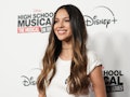 Olivia Rodrigo smiles while wearing a white tee at a Disney event.