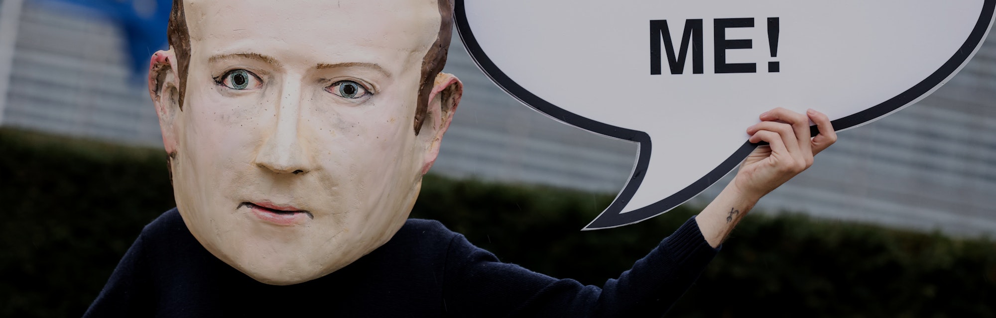 A protester is seen wearing a large sized mask of Facebook CEO Mark Zuckerberg. They are carrying a ...