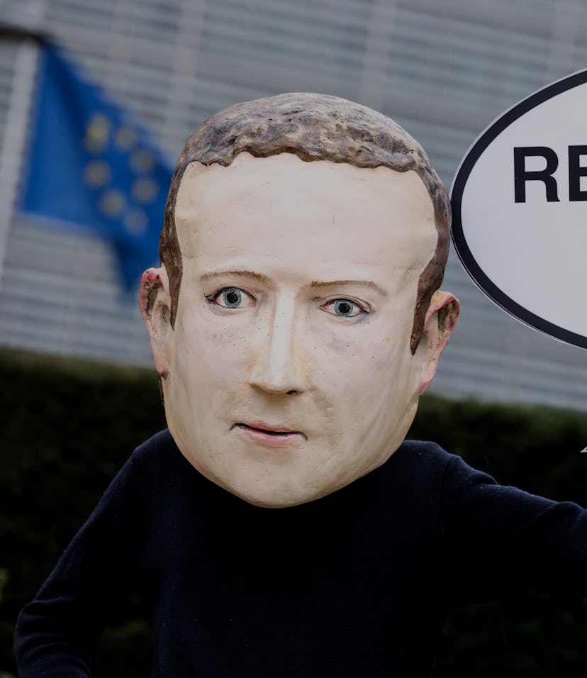 A protester is seen wearing a large sized mask of Facebook CEO Mark Zuckerberg. They are carrying a ...